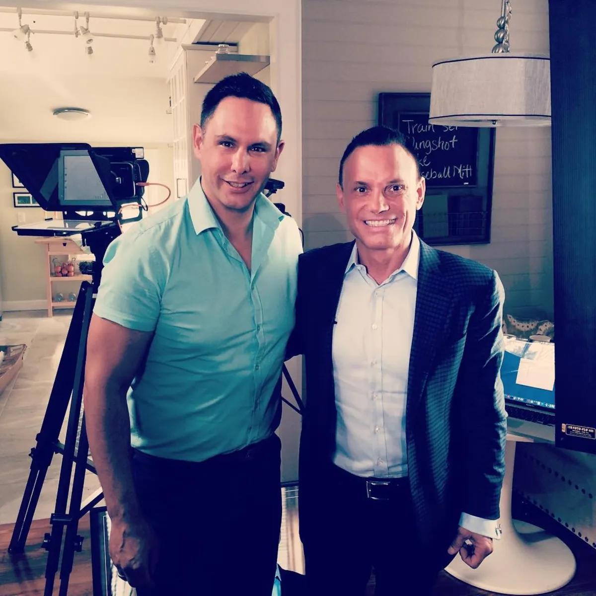 Shane James with Kevin Harrington on a film set, teleprompter and camera rig behind them